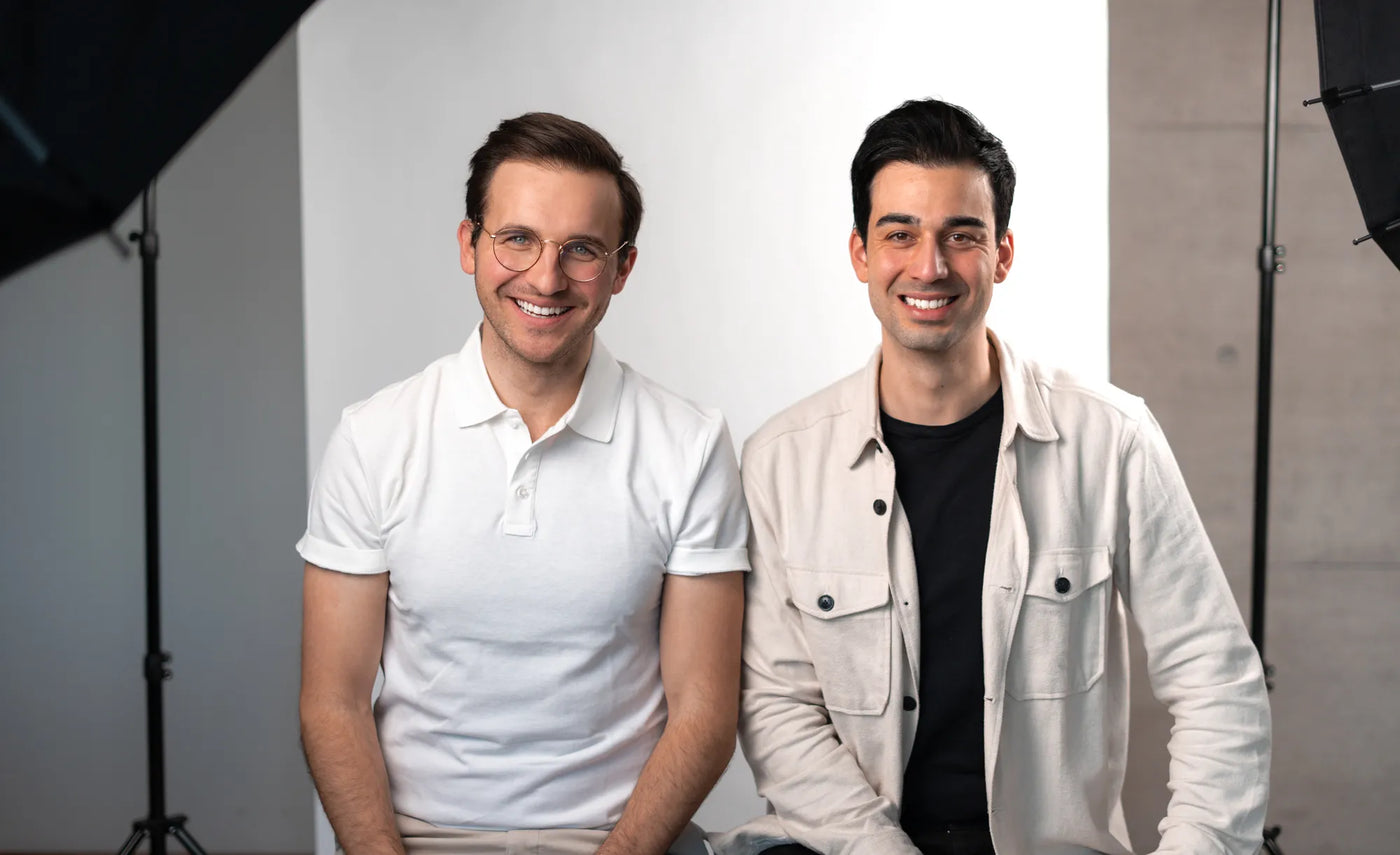Gründer von Paperdent, Louis und Burak, die in einem Fotostudio sitzen und in die Kamera lächeln